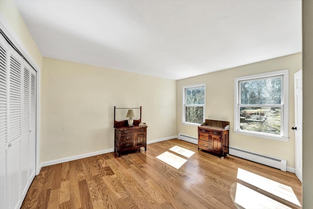 sitting room featuring baseboard heating, baseboards, and wood finished floors