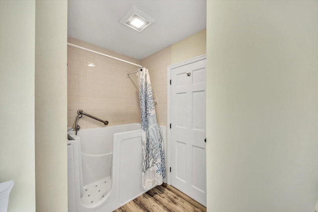 bathroom featuring a bathing tub, a shower with curtain, wood finished floors, and toilet