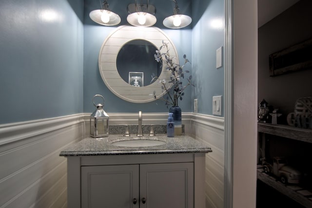 bathroom with vanity, a decorative wall, and wainscoting