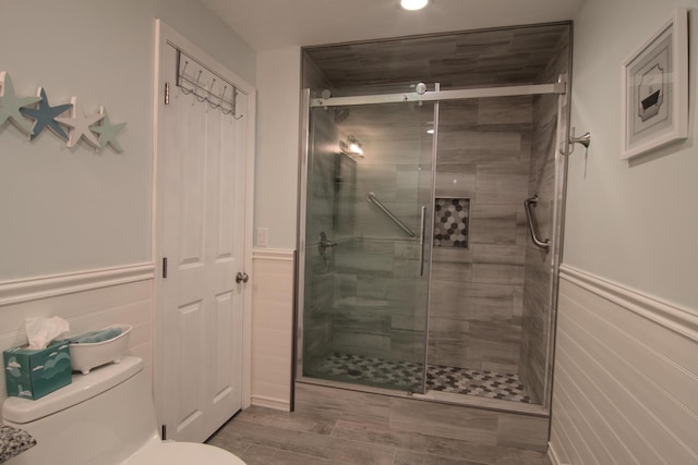 bathroom with a wainscoted wall, toilet, and a stall shower