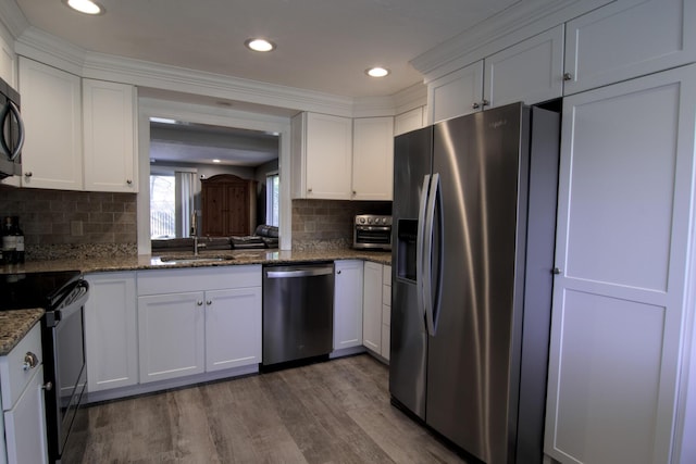 kitchen featuring stone counters, appliances with stainless steel finishes, dark wood-style floors, white cabinetry, and a sink