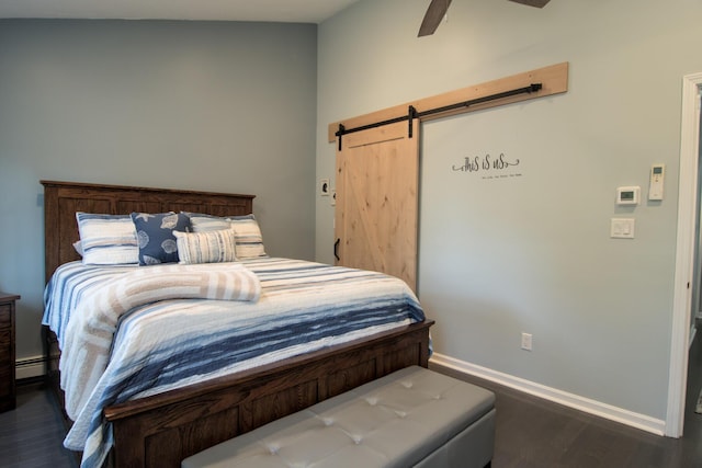 bedroom featuring dark wood finished floors, baseboards, a baseboard heating unit, and a barn door