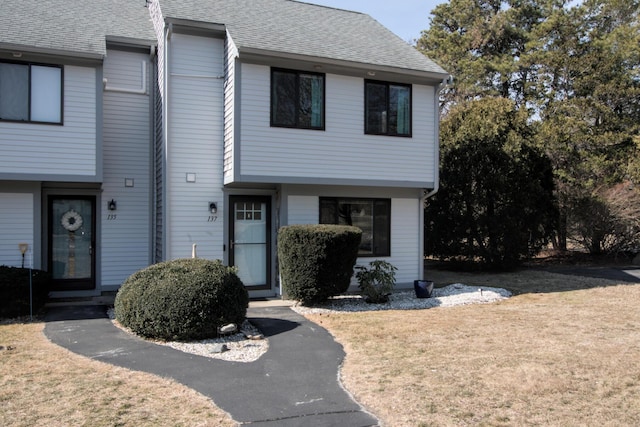 view of front of home featuring a front yard and a shingled roof