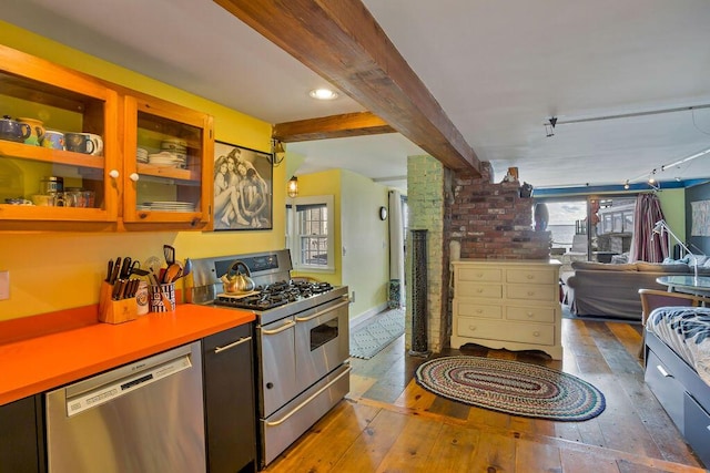 kitchen featuring beam ceiling, rail lighting, dark hardwood / wood-style flooring, and stainless steel appliances