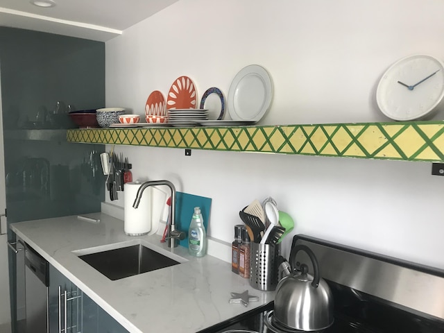 kitchen with sink, light stone counters, range, and stainless steel dishwasher