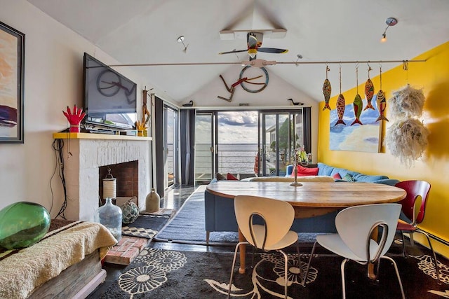 dining space featuring ceiling fan, a brick fireplace, and lofted ceiling