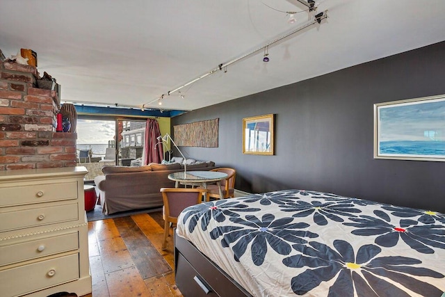 bedroom with hardwood / wood-style floors and track lighting