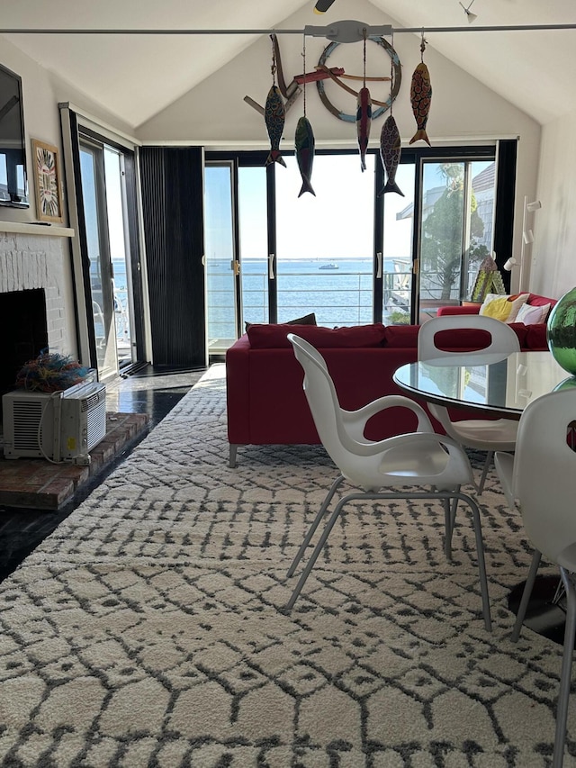 dining space with vaulted ceiling, a water view, and a fireplace