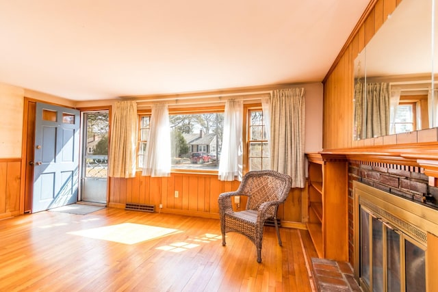 sitting room with a fireplace, hardwood / wood-style floors, visible vents, wainscoting, and wooden walls