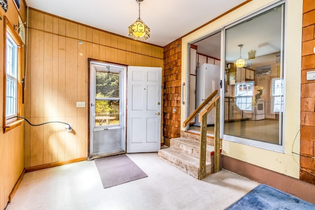 foyer entrance with ornamental molding, stairs, wooden walls, and light floors