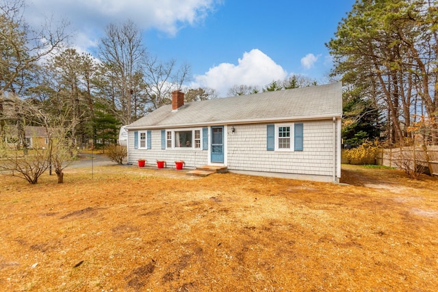 view of front of house with a shingled roof, fence, and a chimney