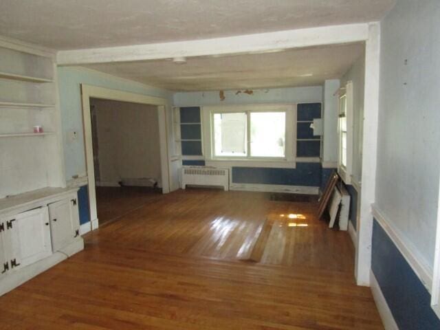 unfurnished living room featuring radiator and dark hardwood / wood-style flooring