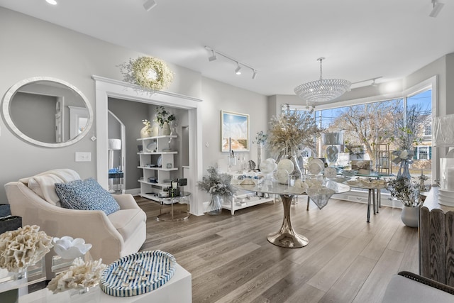 living room featuring an inviting chandelier, track lighting, and wood-type flooring