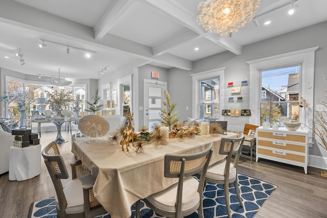 dining area featuring rail lighting, hardwood / wood-style floors, a notable chandelier, and beam ceiling