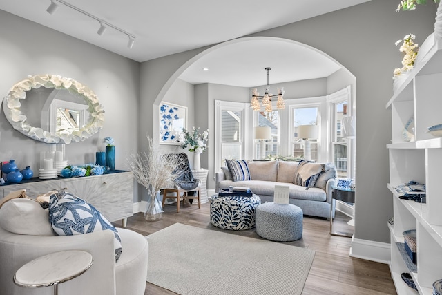 living room featuring a chandelier, track lighting, and light hardwood / wood-style floors