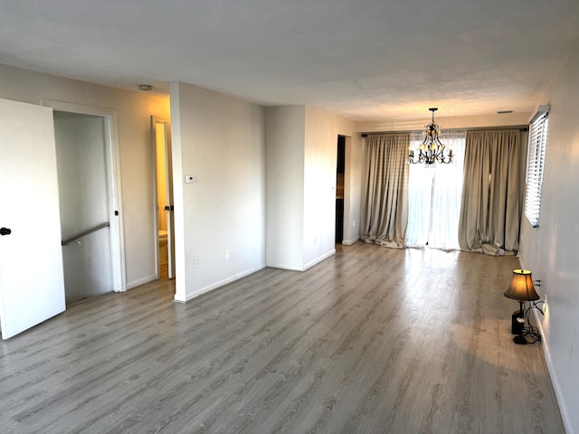 empty room with a notable chandelier and wood-type flooring