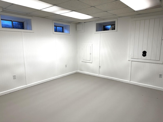 basement with a paneled ceiling and electric panel