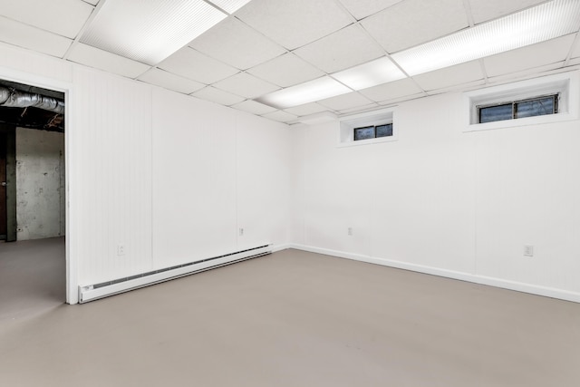 finished basement featuring a baseboard radiator and a paneled ceiling