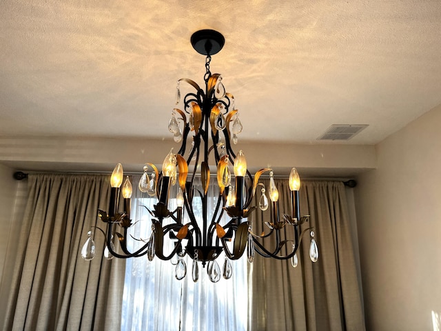 details with a textured ceiling and a chandelier