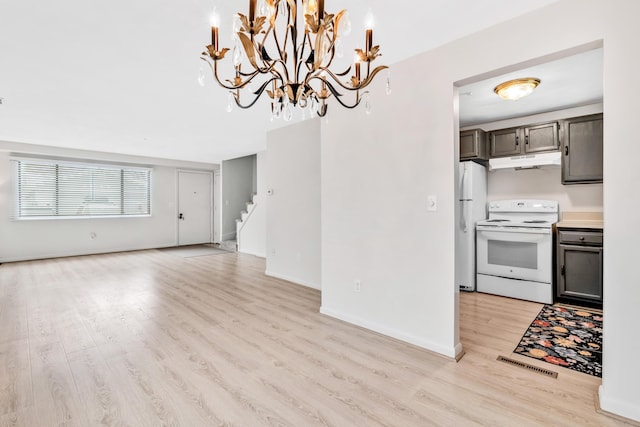 kitchen featuring light wood finished floors, under cabinet range hood, open floor plan, an inviting chandelier, and white appliances