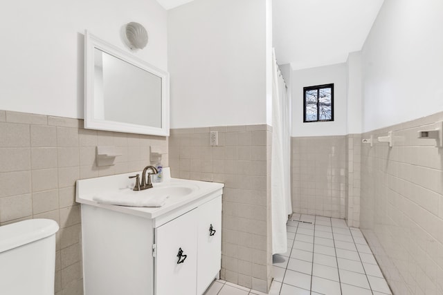 full bath with vanity, tile walls, toilet, and a wainscoted wall