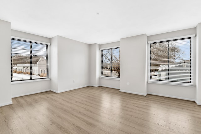 spare room with baseboards and wood finished floors