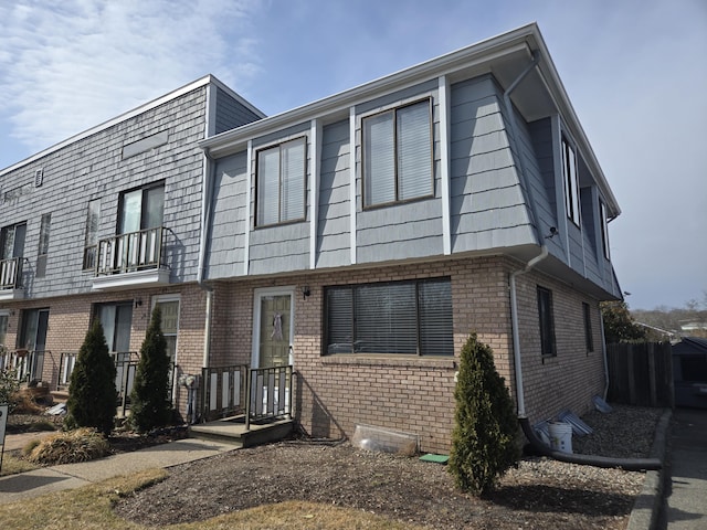 townhome / multi-family property featuring mansard roof, brick siding, and a balcony