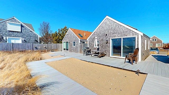 rear view of house featuring a deck and fence