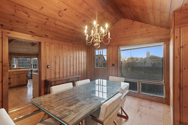 dining space featuring light wood-type flooring, wood walls, a chandelier, vaulted ceiling, and wooden ceiling