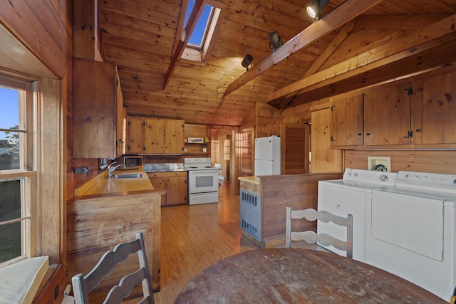 kitchen with white appliances, wooden ceiling, washing machine and clothes dryer, wooden walls, and vaulted ceiling with skylight