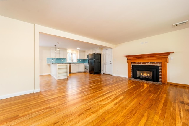 121 S Yarmouth Rd, Dennis, MA 02638 - unfurnished living room featuring light wood-style floors, a fireplace, baseboards, and a sink