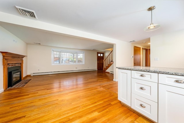 121 S Yarmouth Rd, Dennis, MA 02638 - unfurnished living room featuring a baseboard radiator, light wood-type flooring, stairway, a fireplace with flush hearth, and baseboards