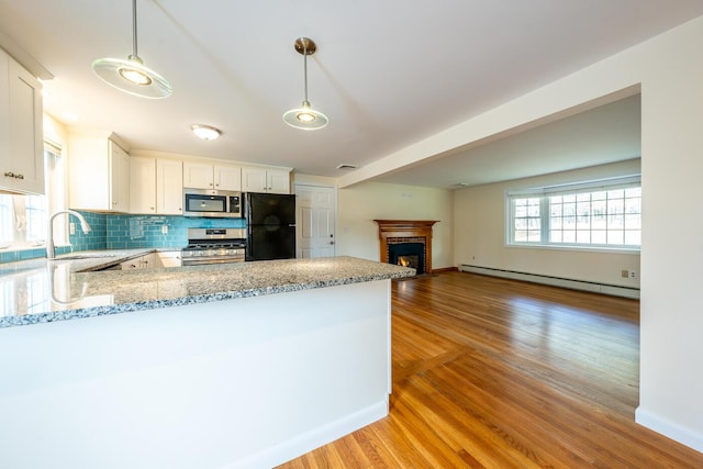 121 S Yarmouth Rd, Dennis, MA 02638 - kitchen featuring appliances with stainless steel finishes, baseboard heating, a sink, light stone countertops, and a peninsula