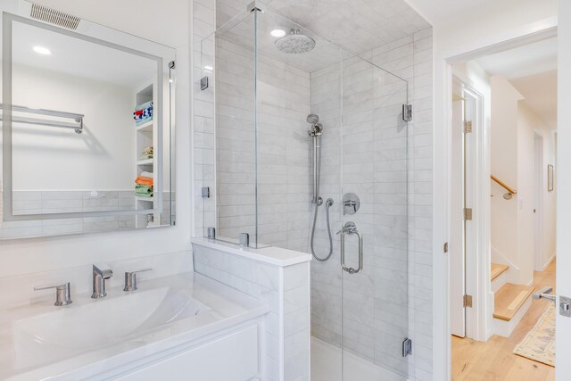 bathroom with wood-type flooring, sink, and an enclosed shower