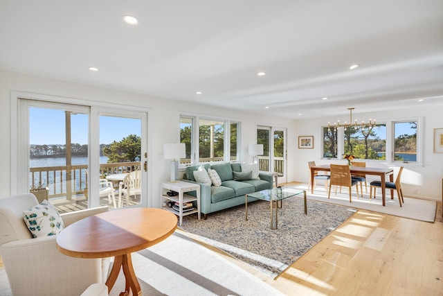 living room featuring a water view, light hardwood / wood-style flooring, and an inviting chandelier