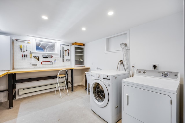 washroom with a workshop area, a baseboard radiator, and washer and dryer