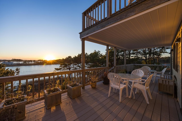 deck at dusk featuring a water view