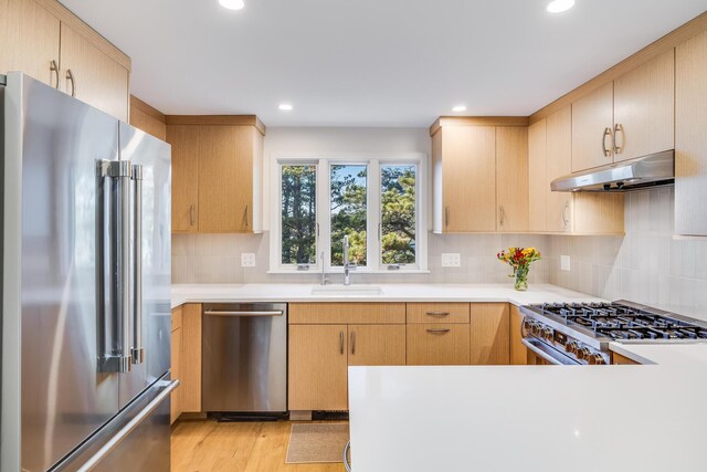 kitchen featuring light brown cabinetry, appliances with stainless steel finishes, tasteful backsplash, sink, and light wood-type flooring