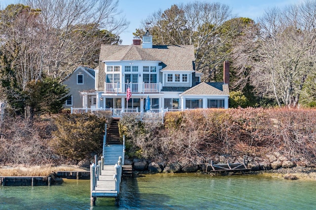 rear view of property with stairway, a water view, a chimney, and a balcony