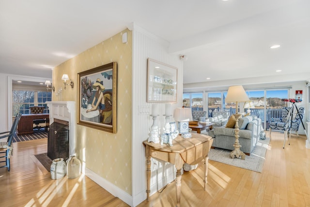 living room featuring recessed lighting, wood finished floors, a fireplace with flush hearth, baseboards, and wallpapered walls