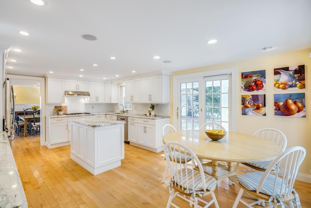 kitchen featuring light wood-style floors, gas stovetop, under cabinet range hood, and a sink