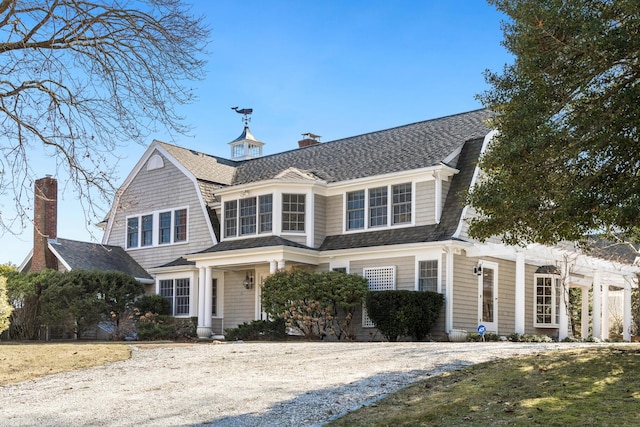 shingle-style home featuring a shingled roof, a chimney, and a gambrel roof