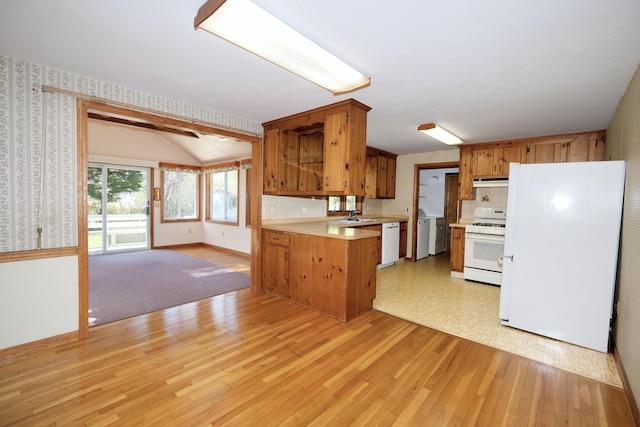 kitchen with white appliances, open floor plan, light countertops, a sink, and light wood-style flooring