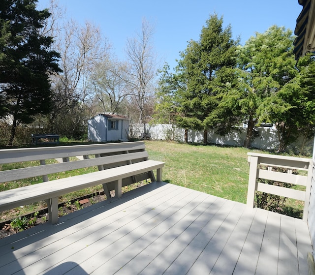 deck featuring a fenced backyard, a storage unit, an outdoor structure, and a lawn
