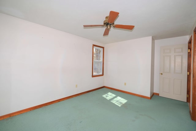 carpeted spare room featuring baseboards and ceiling fan