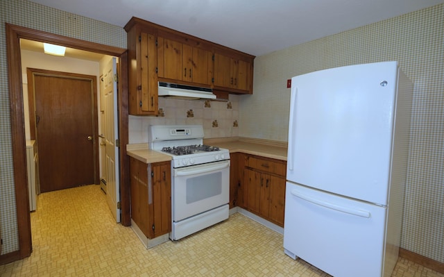 kitchen with light countertops, light floors, under cabinet range hood, and white appliances