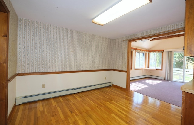unfurnished room featuring wallpapered walls, baseboard heating, and wood finished floors