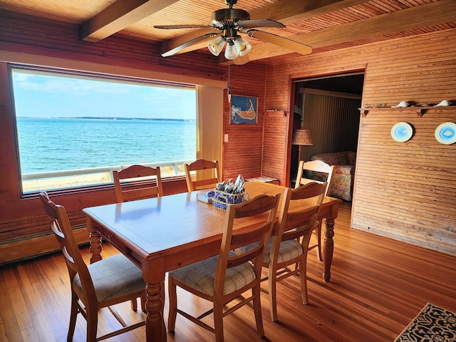 dining space with wood-type flooring, beamed ceiling, a water view, ceiling fan, and wooden ceiling