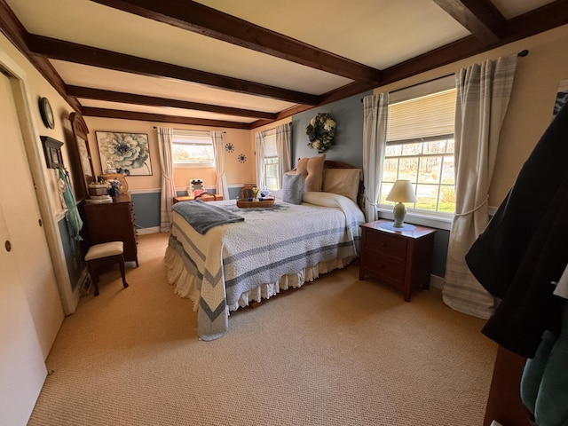 bedroom with light colored carpet, beam ceiling, and multiple windows