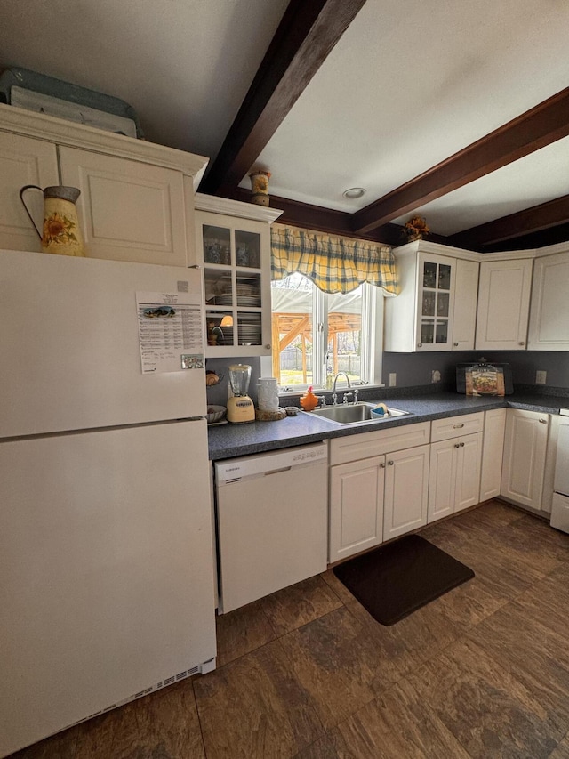 kitchen with dark countertops, glass insert cabinets, white appliances, beamed ceiling, and white cabinets